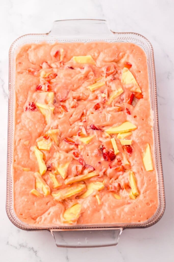 Strawberries and white chocolate being swirled into batter.