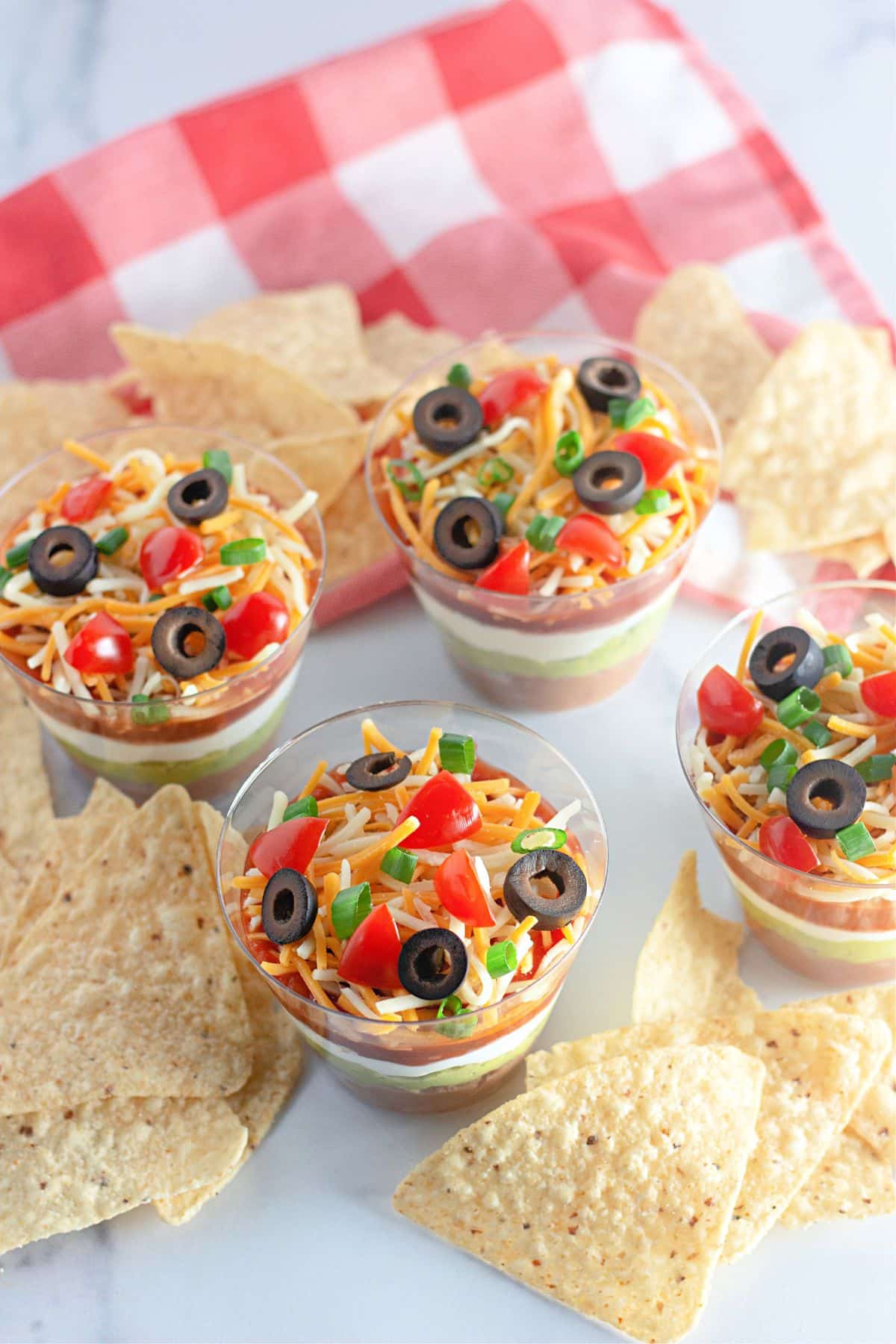 7 Layer dip cups and tortillas chips on a counter.