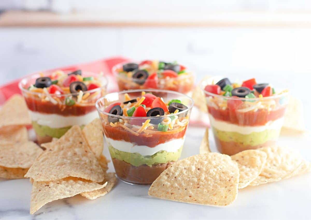 7 Layer dip cups and tortillas chips on a counter.