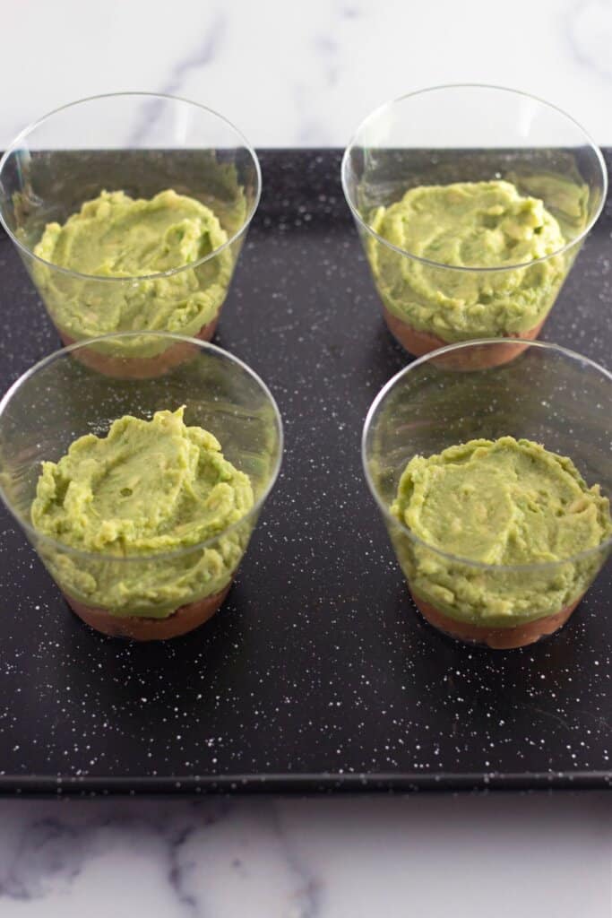 Guacamole being spread on top of refried beans.