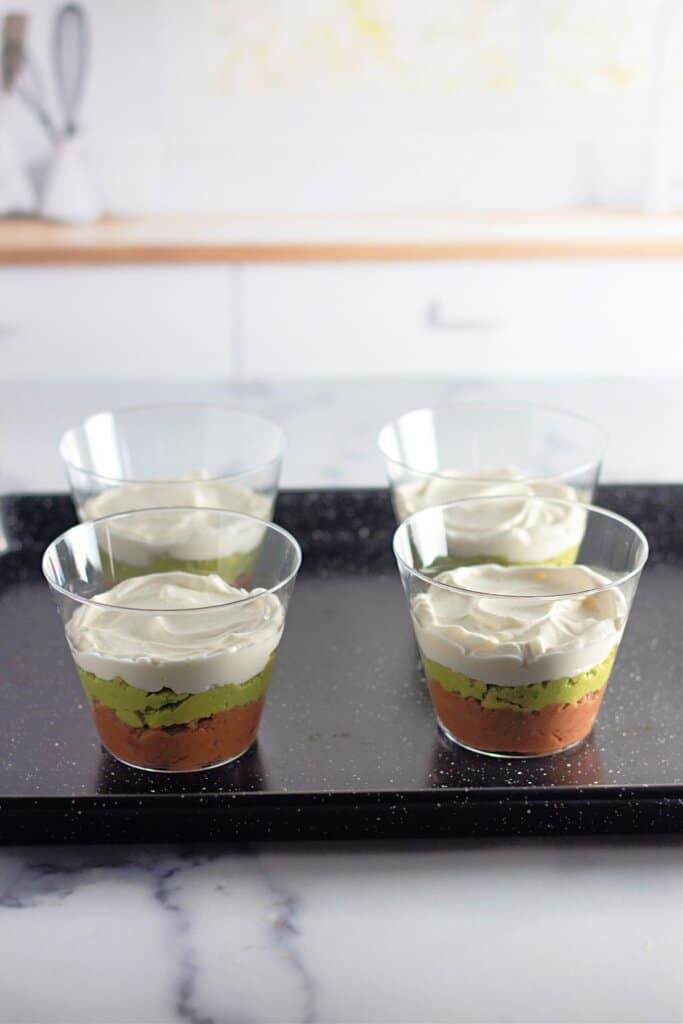 Sour cream being spread on top of guacamole.