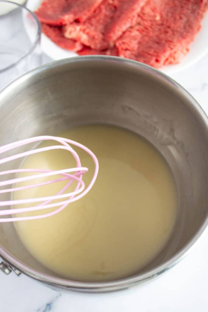 Flour being added to oil in a saucepan.