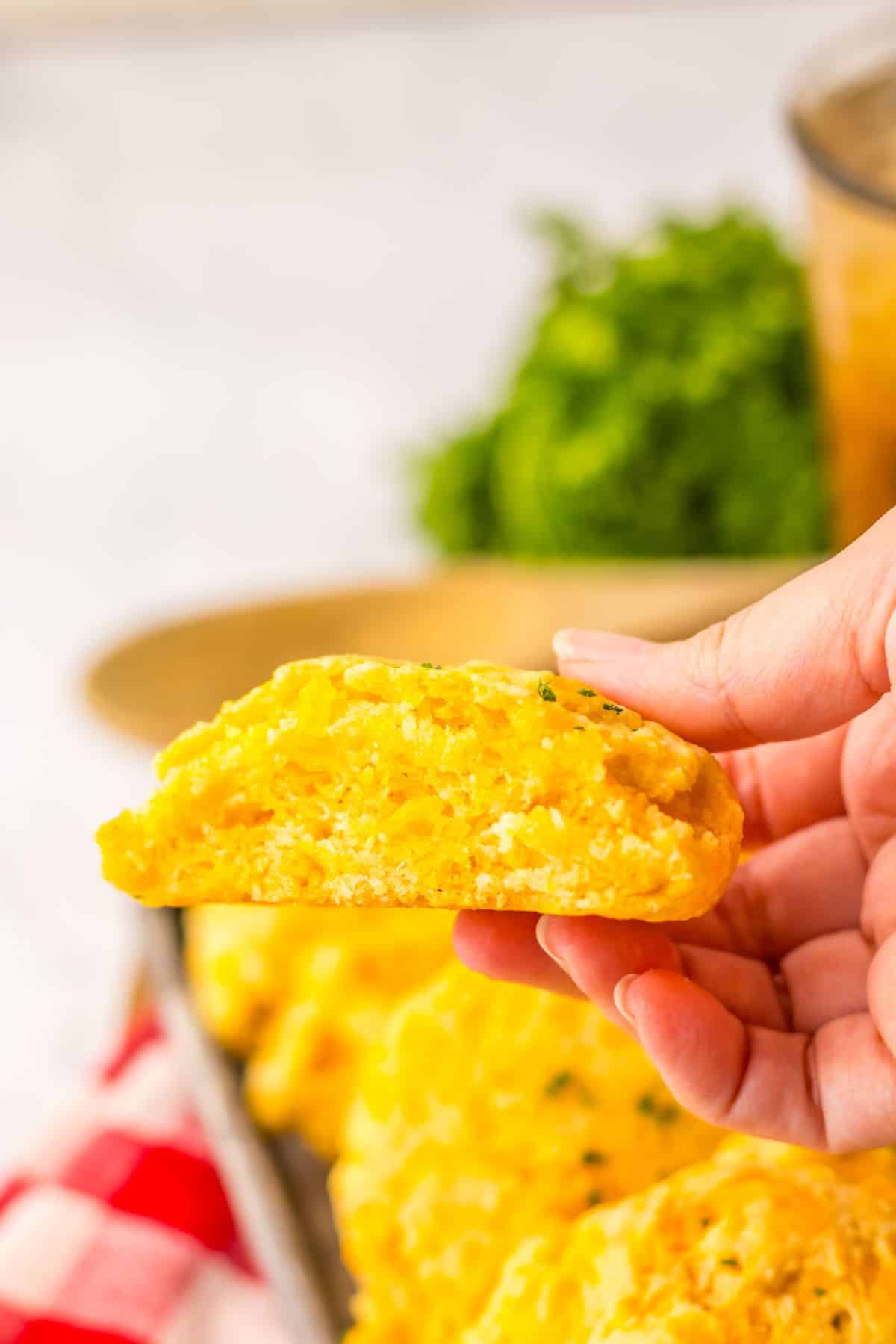 Cheddar bay biscuit in a women's hand held in the air.