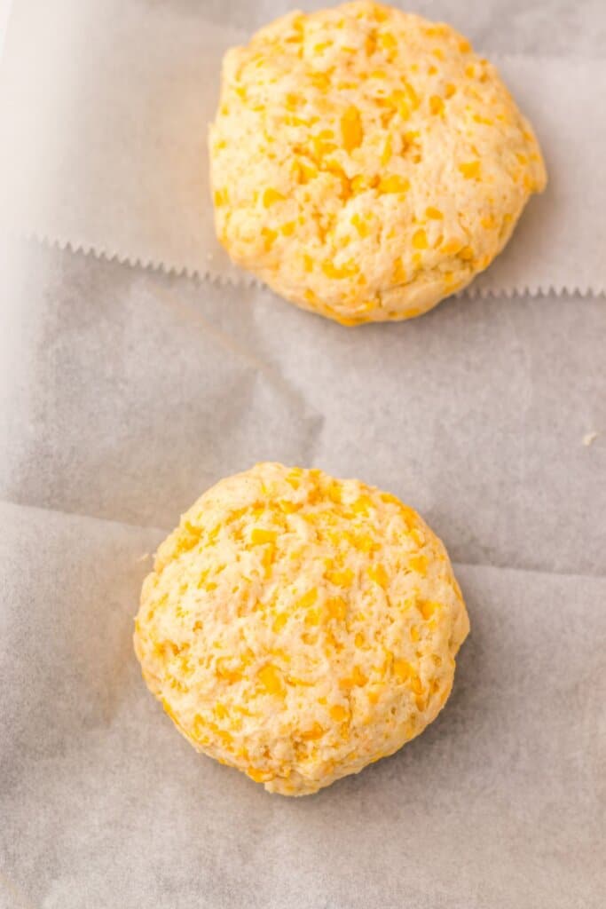 Raw biscuit dough on a parchment lined baking sheet.
