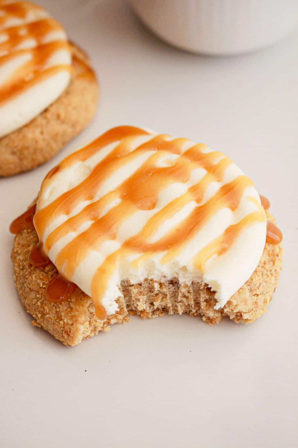 Cheesecake cookie on a counter with a bite missing.