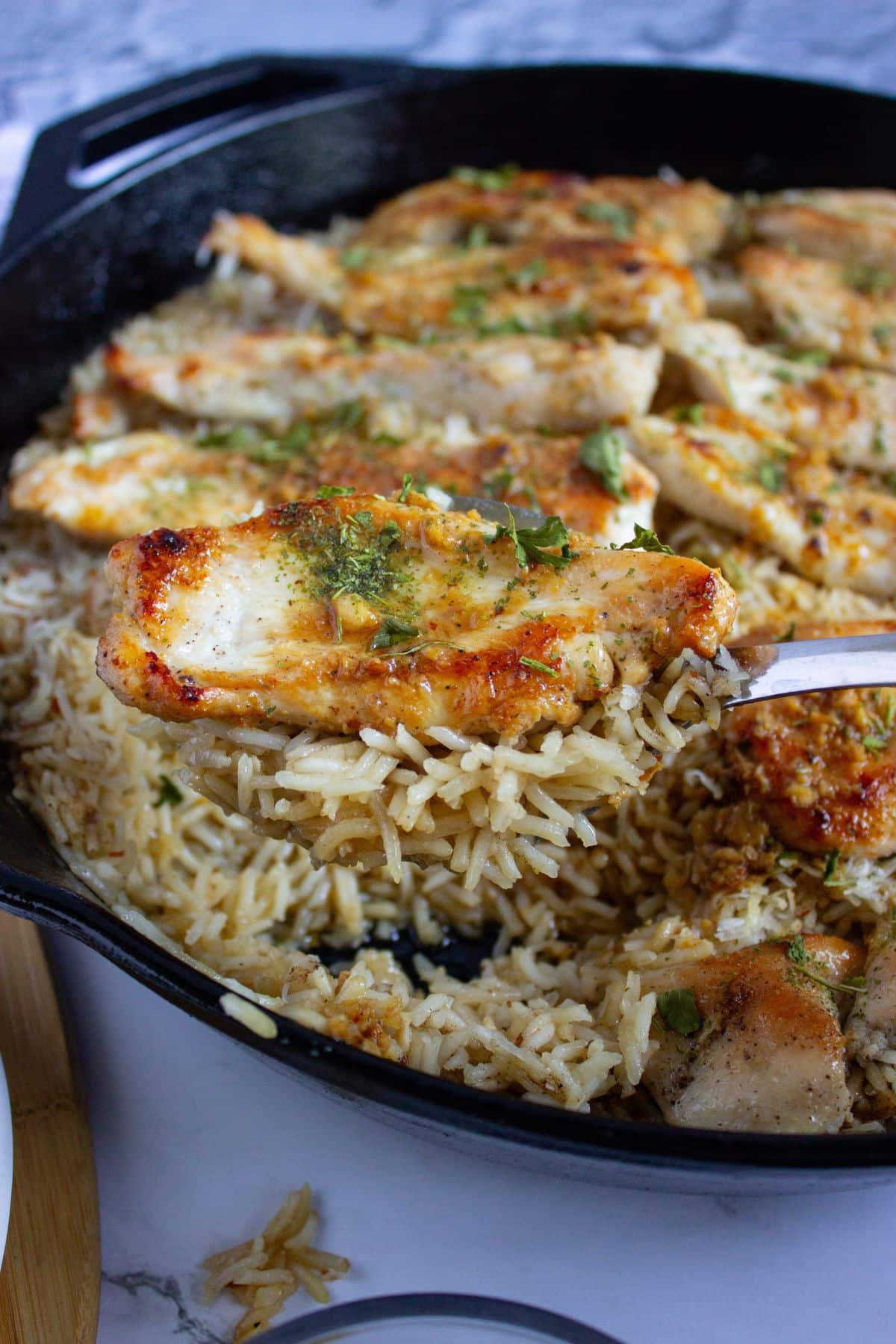 Chicken tenderloin and rice being removed from the skillet.