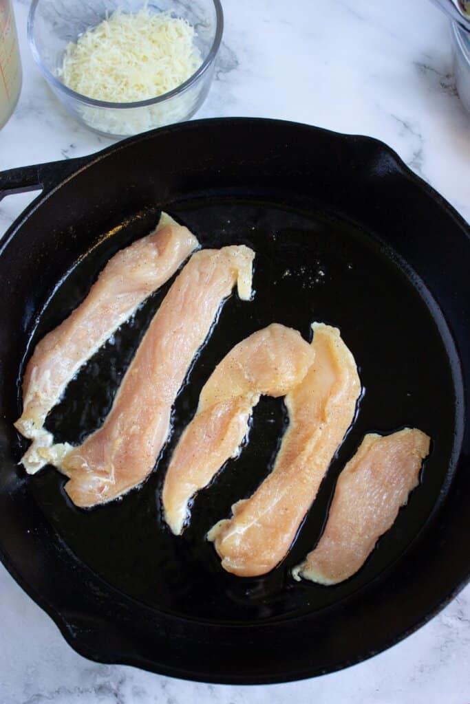 Tenders being cooked in a large skillet.