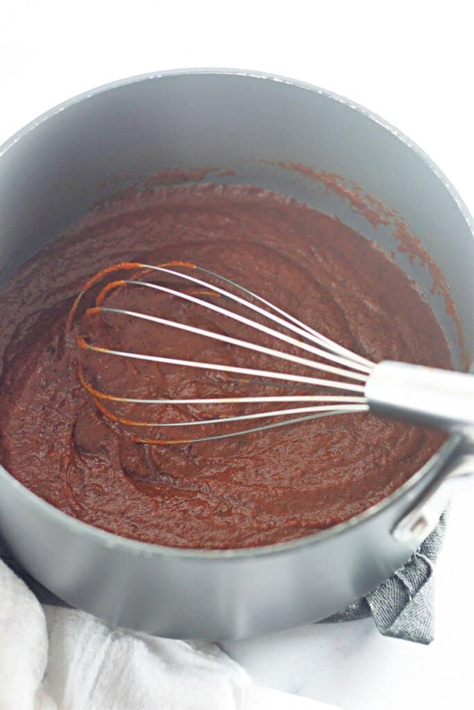 Red sauce being cooked in a saucepan.