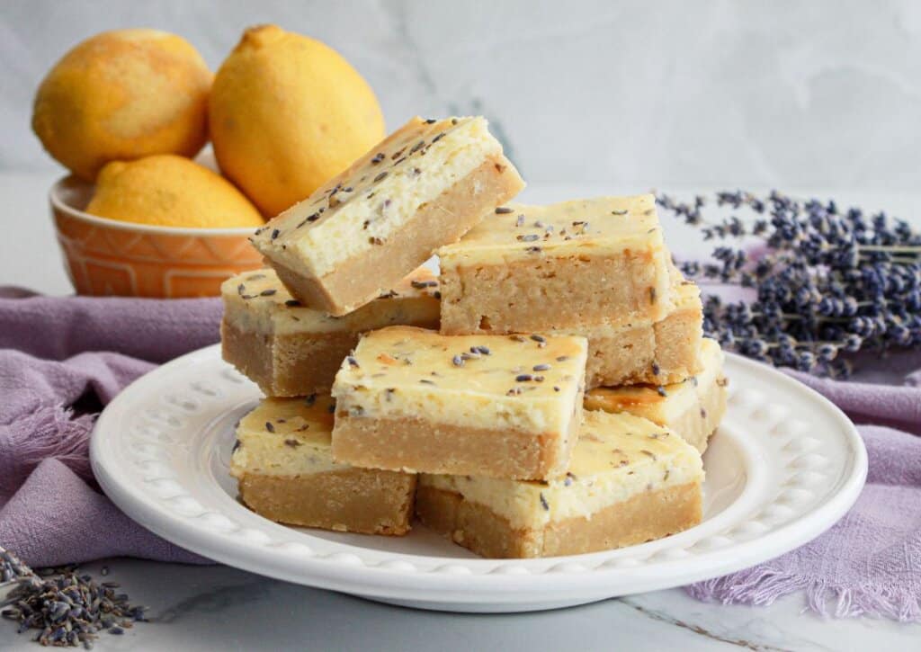 Lemon cheesecake bars with lavendar on a white plate.