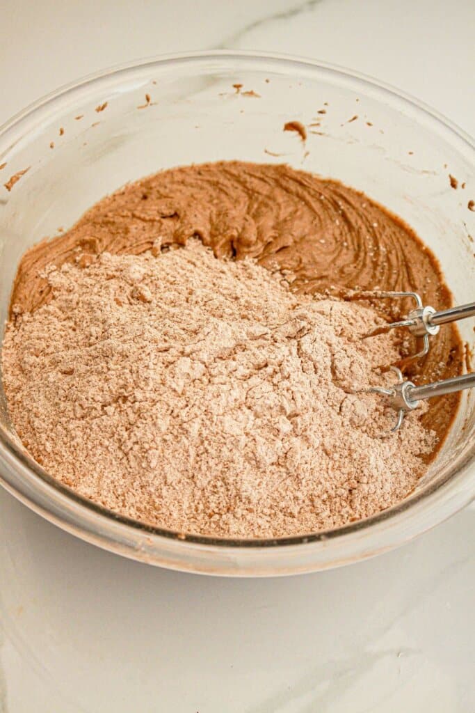 Dry ingredients being added wet ingredients in a glass bowl.