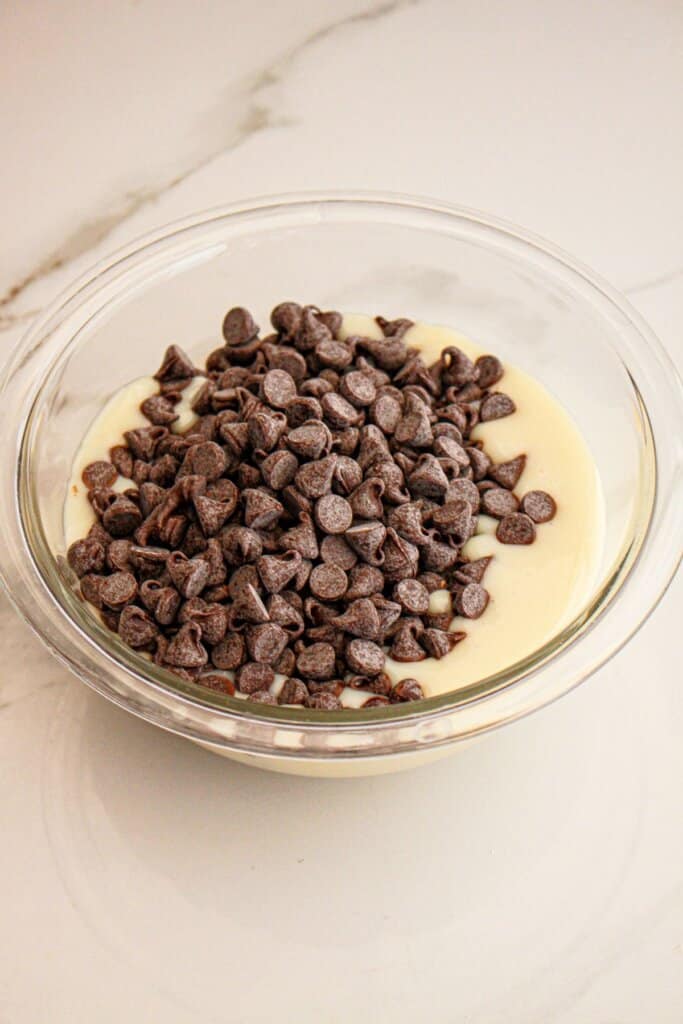 Sweetened condensed milk and chocolate chips in a glass bowl.