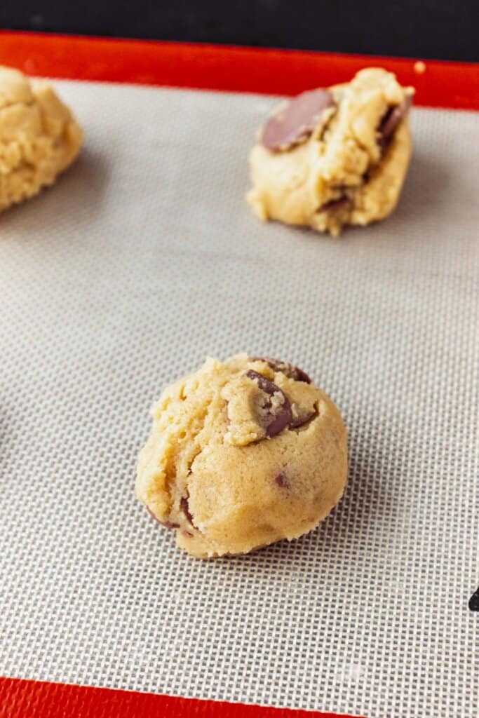 Dough balls on a silicone baking mat lined baking sheet.
