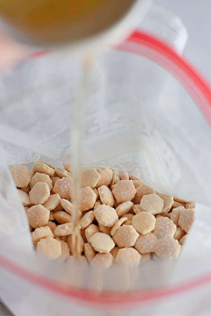 Oil being added to crackers in a storage bag.
