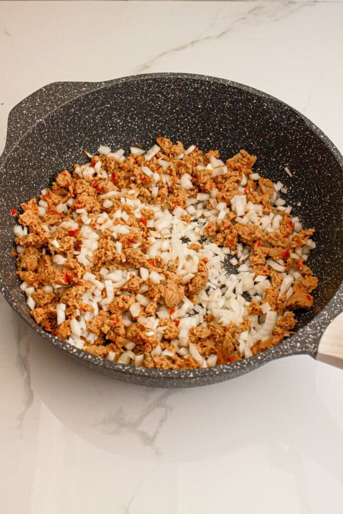 Sausage and onions being cooked in a skillet.