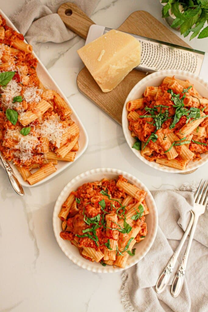 Two small plates full of rigatoni topped with fresh basil.