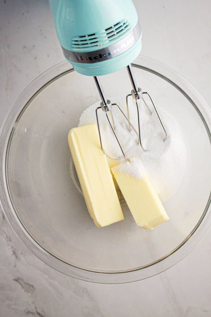 Butter and sugar in a glass mixing bowl.