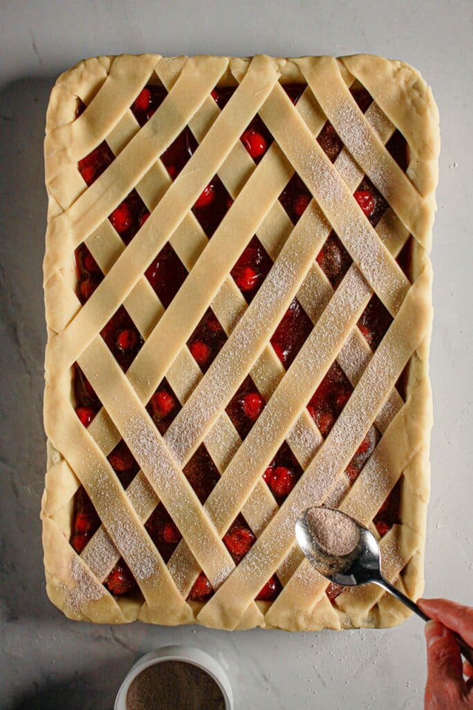 Cinnamon sugar being sprinkled on top of a pie.