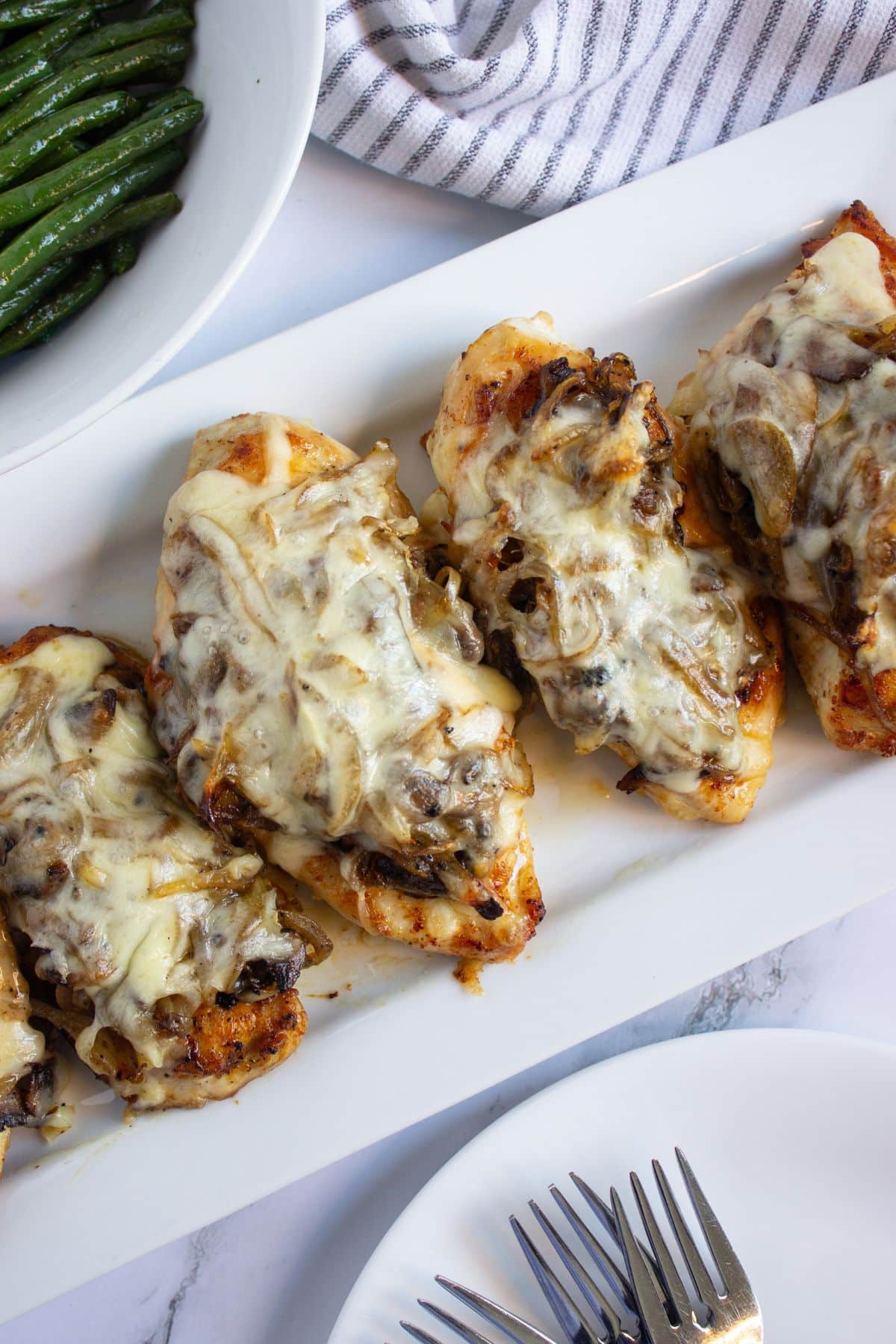 Five pieces of smothered chicken on a white serving platter.