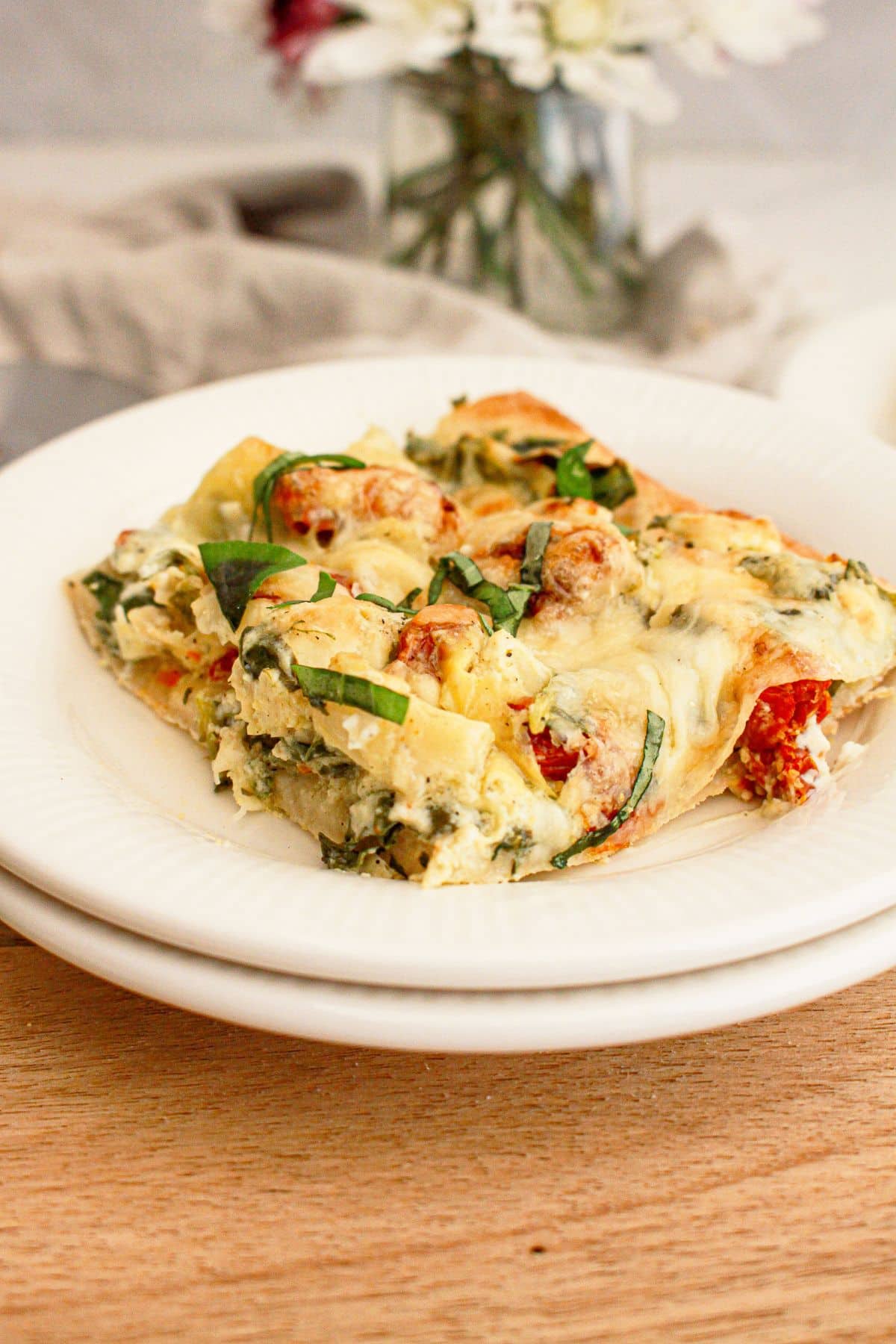 Slice of spinach artichoke pizza on a plate.