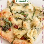 Slice of spinach artichoke pizza on a plate.
