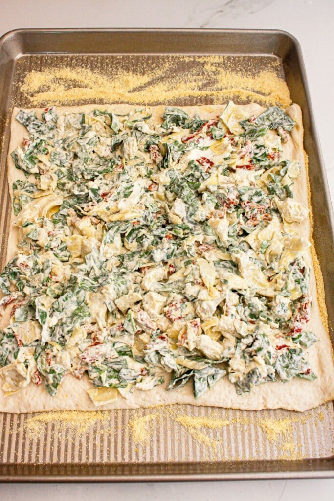 Pizza on a baking sheet ready to cook.
