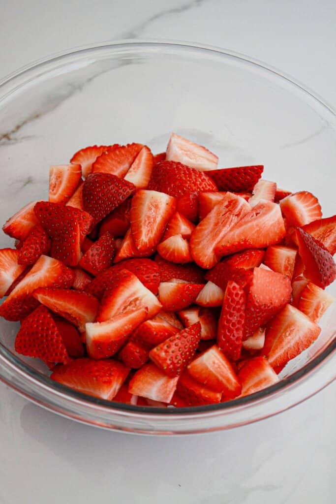 Fresh strawberries and rhubarb slices in a glass bowl.
