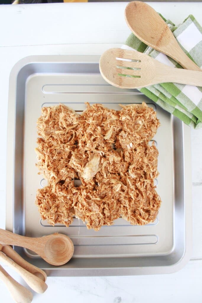 Shredded meat being added to the top of buns.