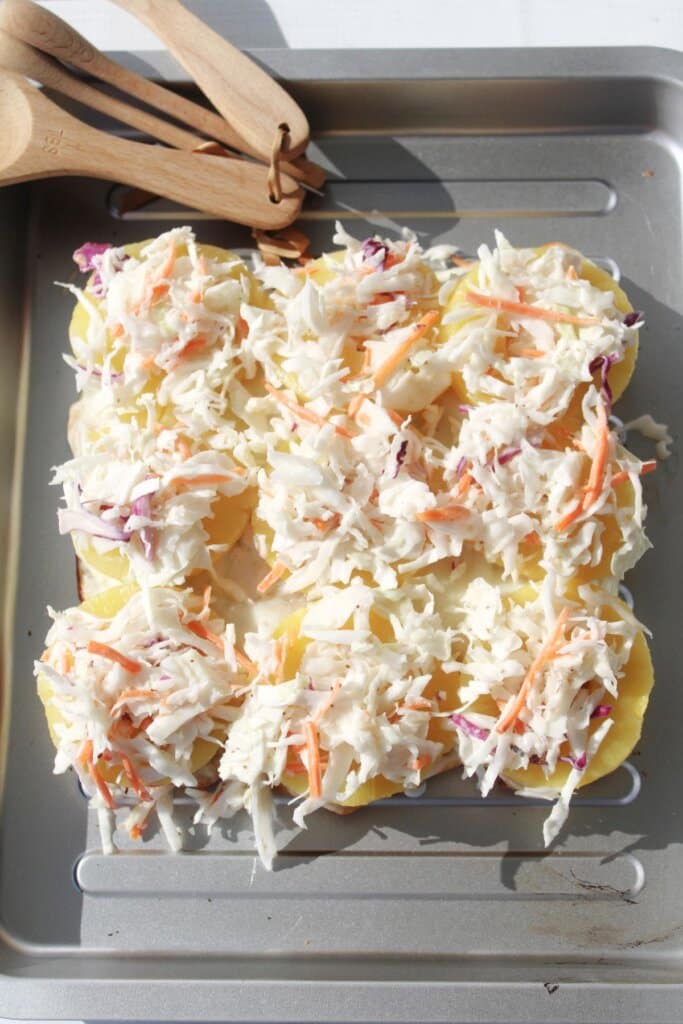 Coleslaw being added to the top of pineapple slices on buns.