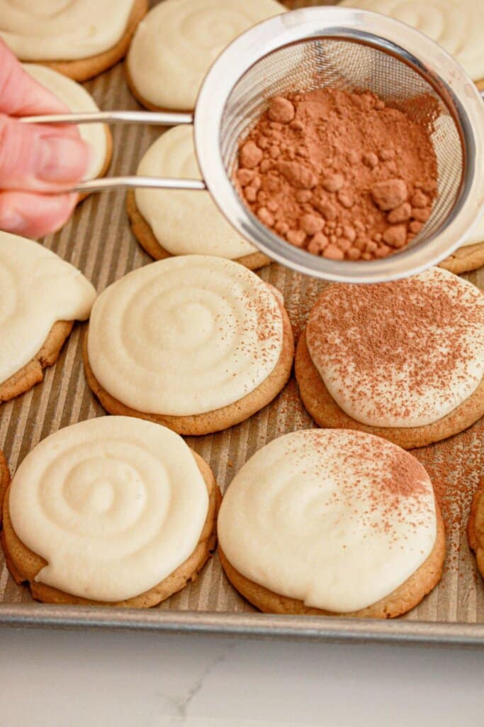 Cocoa powder being dusted on top cookies.