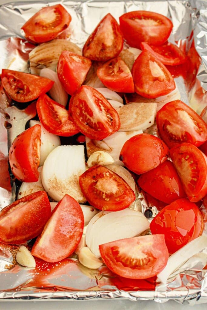 Tomatoes and onions on a baking sheet.