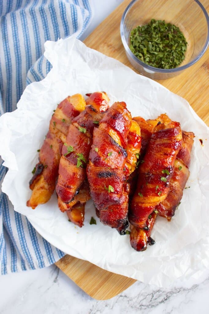 Bacon wrapped chicken tenders on a plate topped with paper towels.