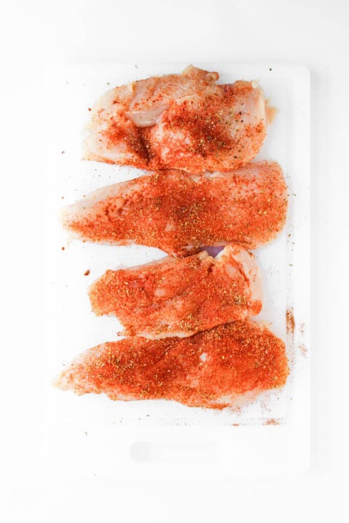 Seasoning being sprinkled on top of raw meat.