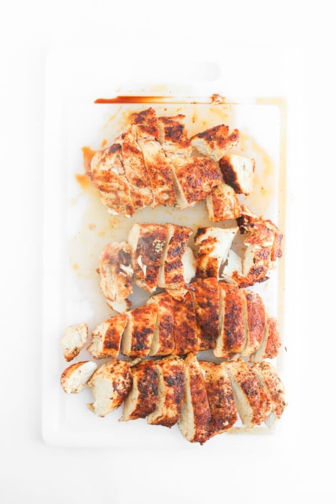 Cooked chicken breasts being sliced on a cutting board.