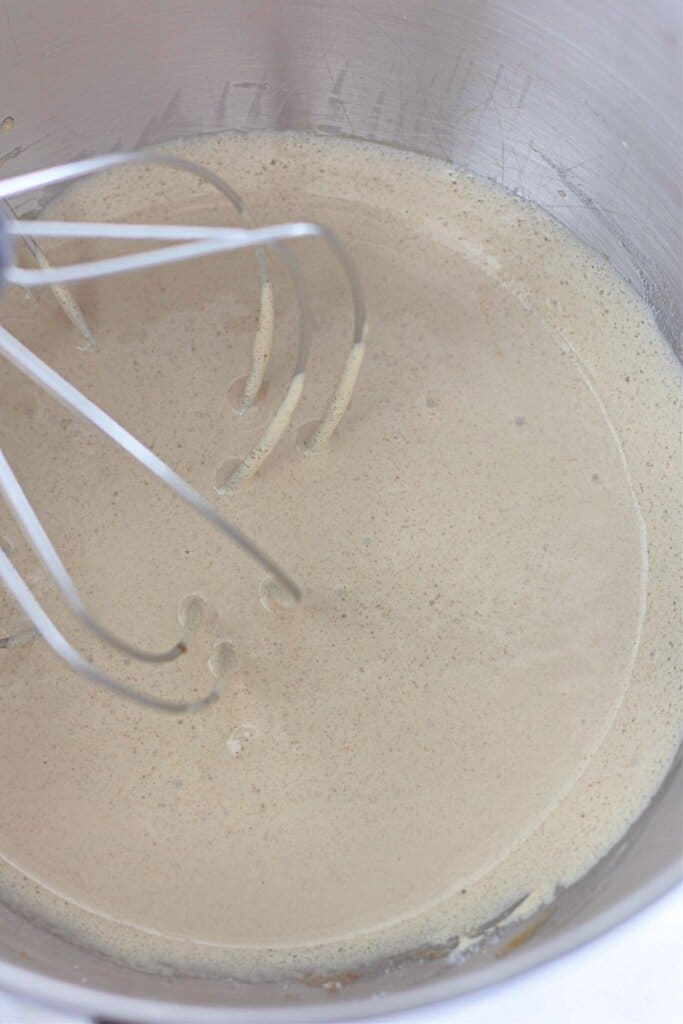 Sugar and eggs being mixed in a stand mixer.