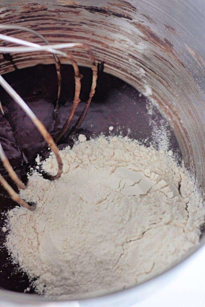 Flour being added to dough in a stand mixer.