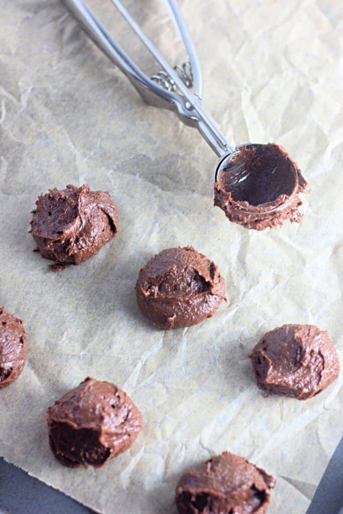 Dough being scooped in mounds on a baking sheet.