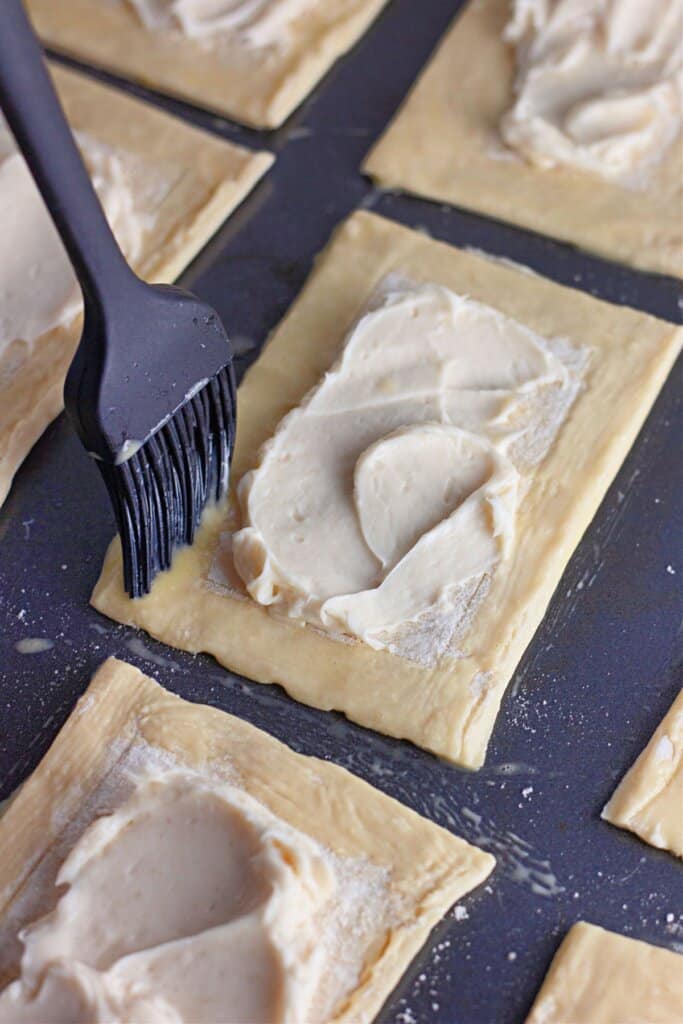 Egg wash being brushed on top of pastry.