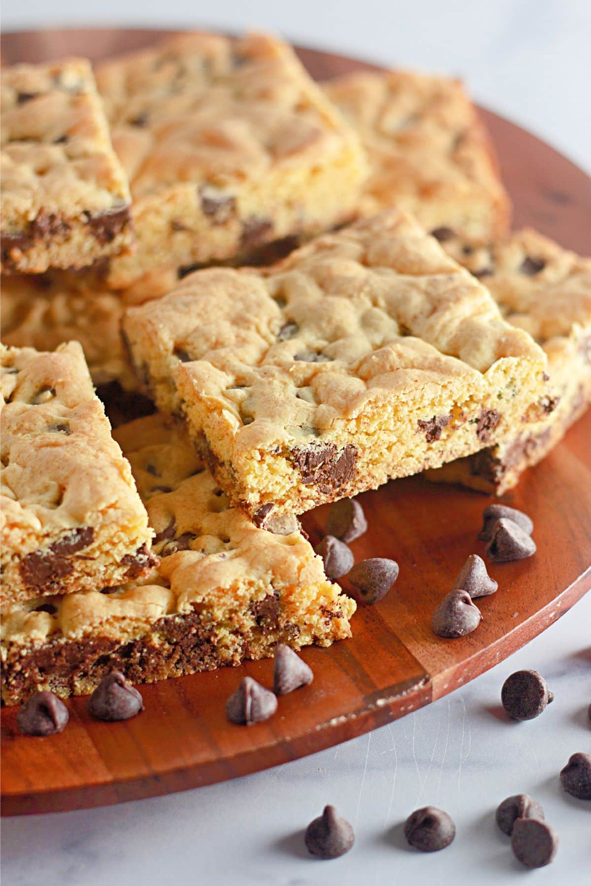 Chocolate chip cookie bars on a wooden cutting board.