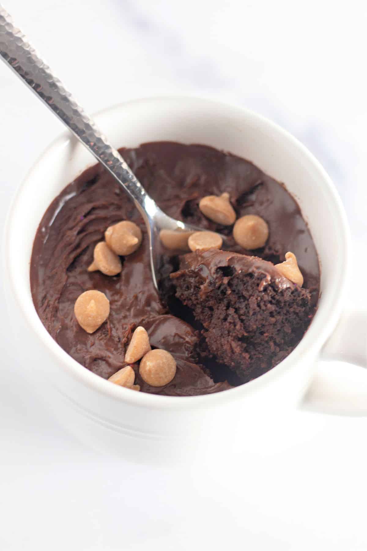 Spoonful of chocolate mug cake being removed from a coffee cup.
