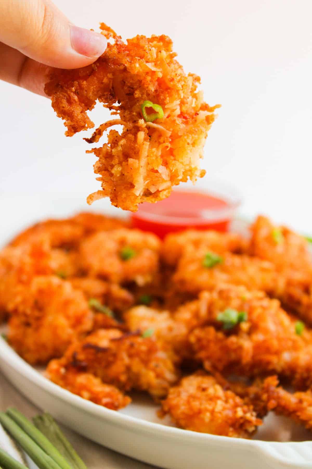 Coconut shrimp held in a woman's hand.