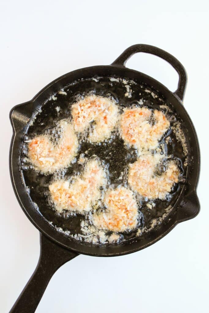 Seafood being fried in a cast iron skillet.