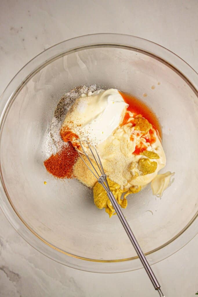 Dressing ingredients being mixed in a large glass bowl.