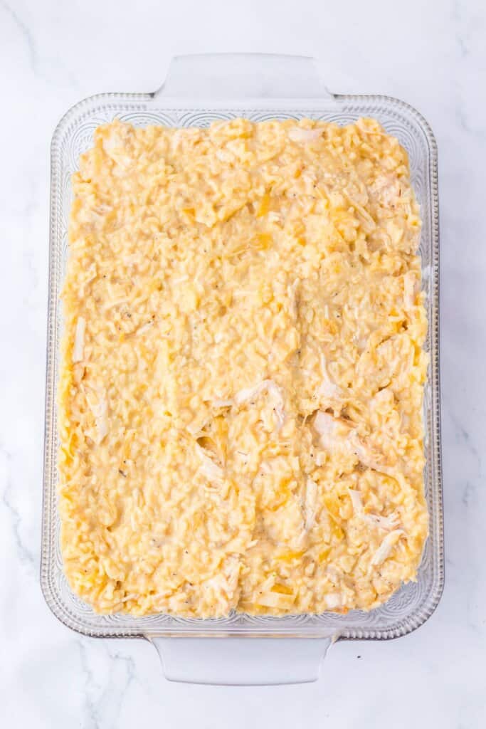 Ingredients being spread into a glass baking dish.