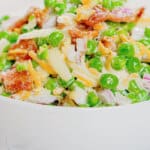 White bowl full of green pea salad.