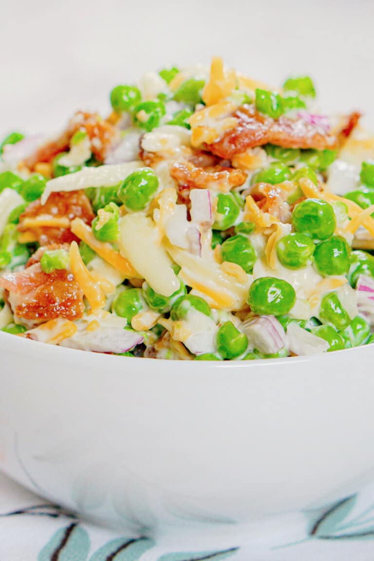 White bowl full of green pea salad.