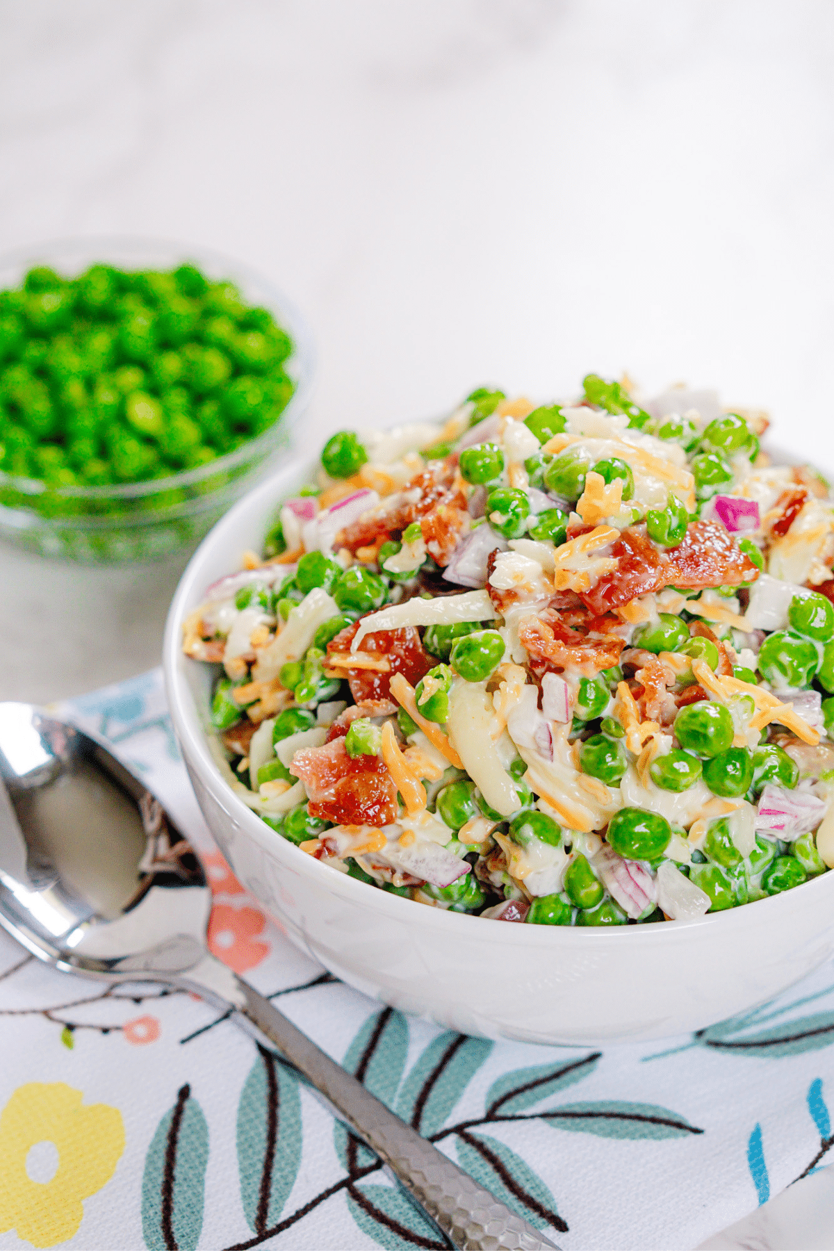 White bowl full of green pea salad.