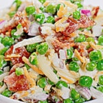 White bowl full of green pea salad.