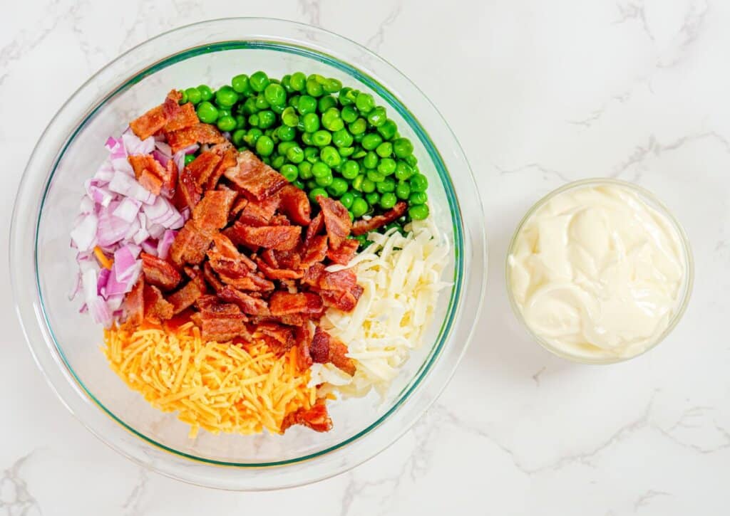 Bacon, cheese, and red onion in a glass bowl.