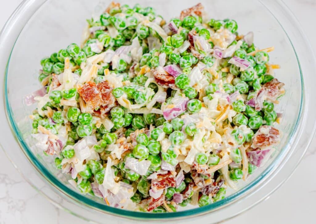 Glass bowl with salad being mixed in it.
