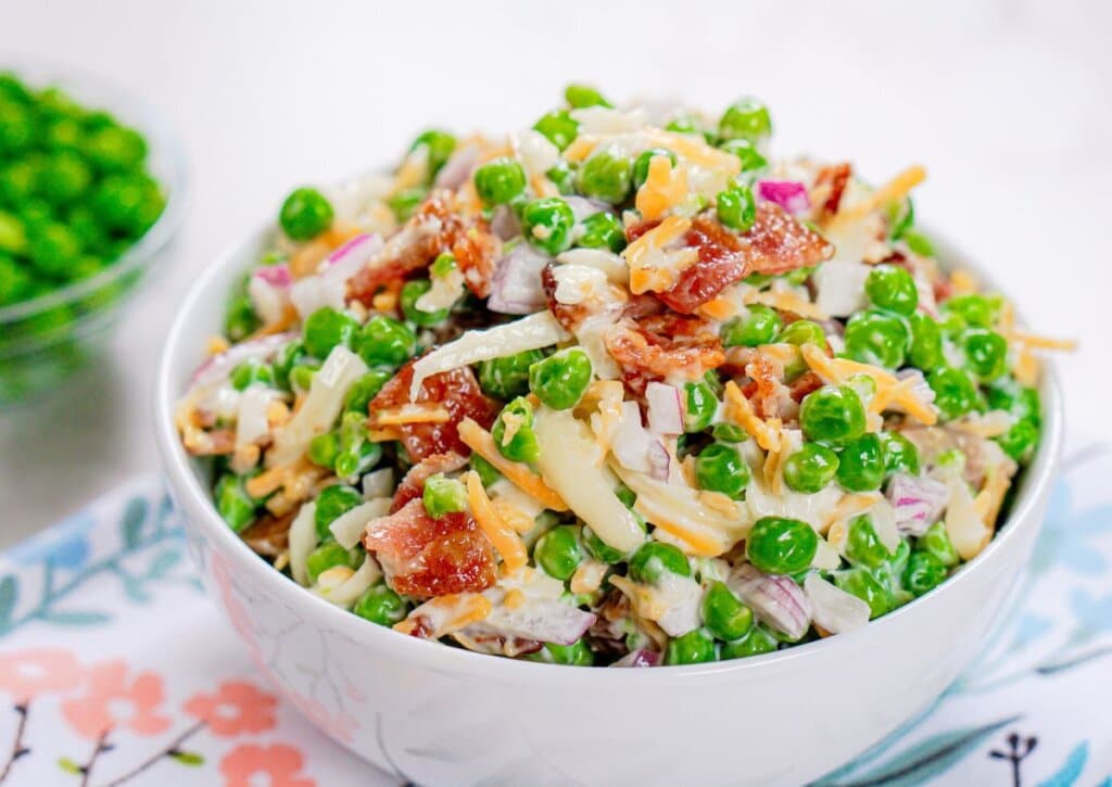 White bowl full of green pea salad.
